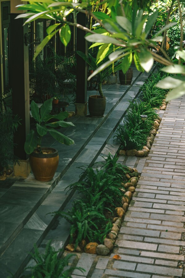A pathway lined with potted plants and a brick border. - Su Retreat Hoi An - Riverfront Resort (Da Nang)