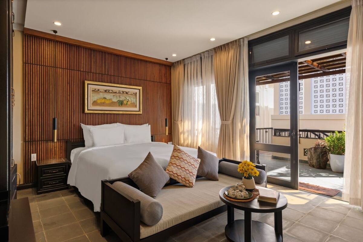 A hotel room with a bed, sofa, and a small table with flowers.