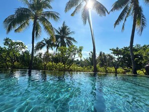 A clear pool surrounded by palm trees and lush greenery. - Su Retreat Hoi An - Riverfront Resort (Da Nang)
