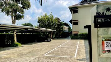 A parking area with a paved surface, a covered car parking structure, and a building with a sign indicating 'Hideaway Resort Ban'.