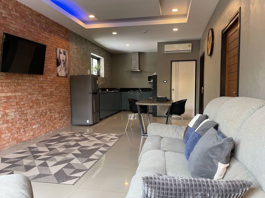 Una sala moderna con un sofá gris, alfombra estampada y una pared de ladrillo decorativa.