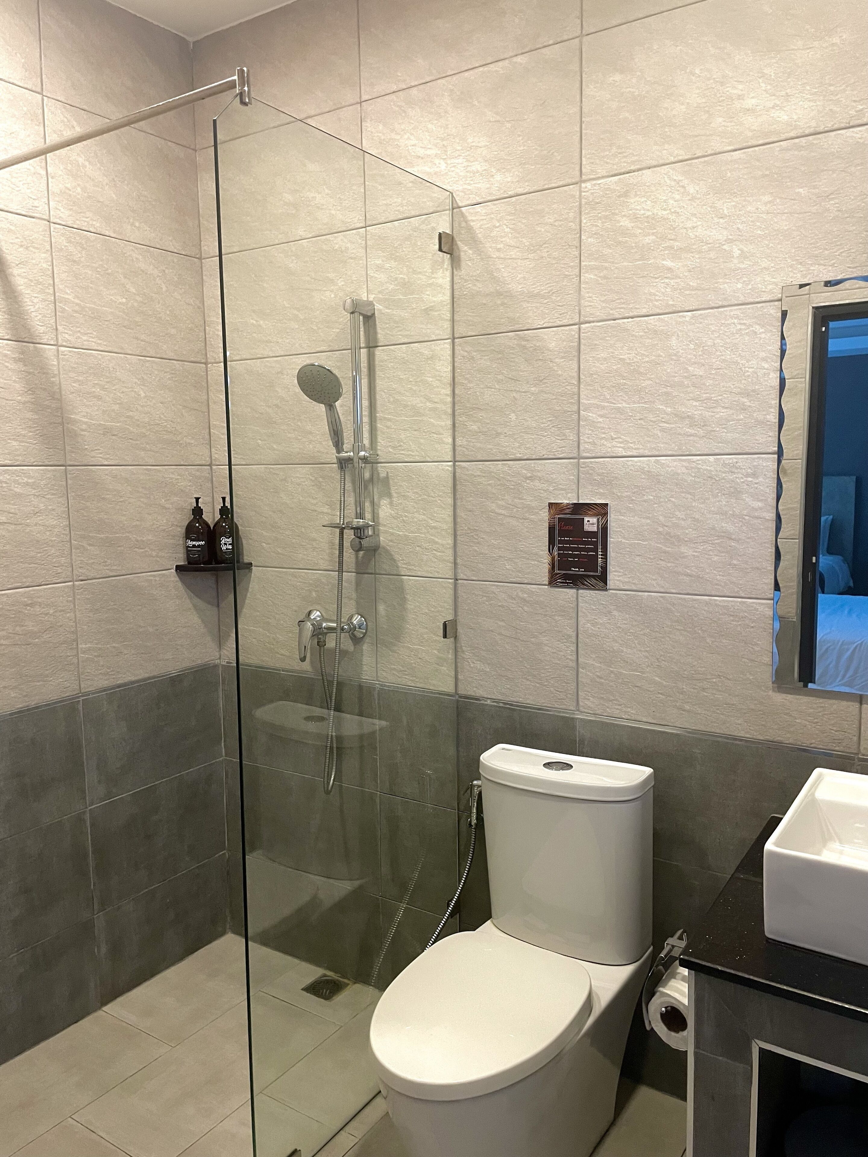 A modern bathroom with a glass-enclosed shower, a white toilet, and a black countertop with a sink.