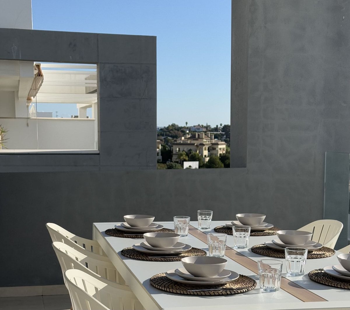 A dining area with a table set for four, a view of a cityscape through a window, and a modern architectural design.
