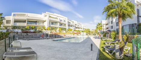 Un hôtel moderne doté d’une piscine, d’un espace extérieur aménagé et de palmiers.
