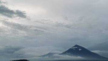 A mountain with a lake in the foreground and a cloudy sky.