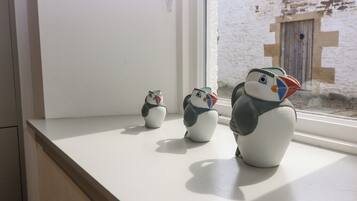 Tres figures de pingüins de ceràmica sobre un davell blanc.