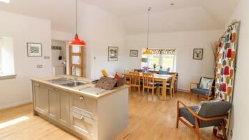 A modern kitchen with a central island, wooden dining table, and chairs.