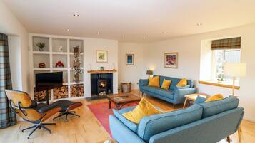 A living room with a sofa, armchairs, a fireplace, and a television.