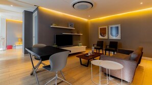 Ein modernes Wohnzimmer mit Flachbildfernseher, einer Couch, einem Couchtisch und einem Essbereich mit Tisch und Stühlen.