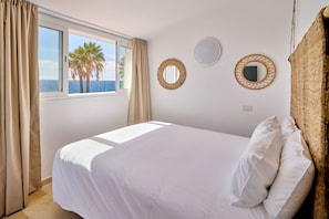Un dormitorio con cama, una ventana con cortinas y dos espejos fijados a la pared.
