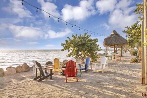 Een strandsetting met kleurrijke Adirondack-stoelen, een rieten constructie en een lichtslingering.