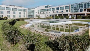 Un bâtiment moderne à plusieurs étages, doté d’une cour intérieure avec un bassin décoratif et d’un espace verdoyant bien entretenu.