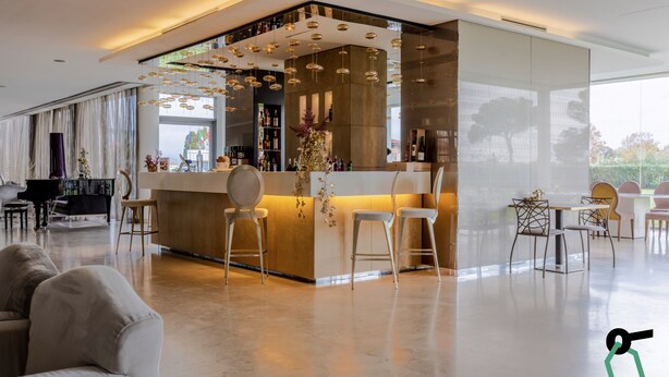 Un espace bar moderne doté d’un comptoir central, de tabourets de bar et d’un luminaire décoratif.