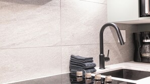 A modern kitchen with a black faucet, a sink, and a stack of folded towels. - Hearthstone Lodge #406 | 3 Peaks Rentals (Sun Peaks)