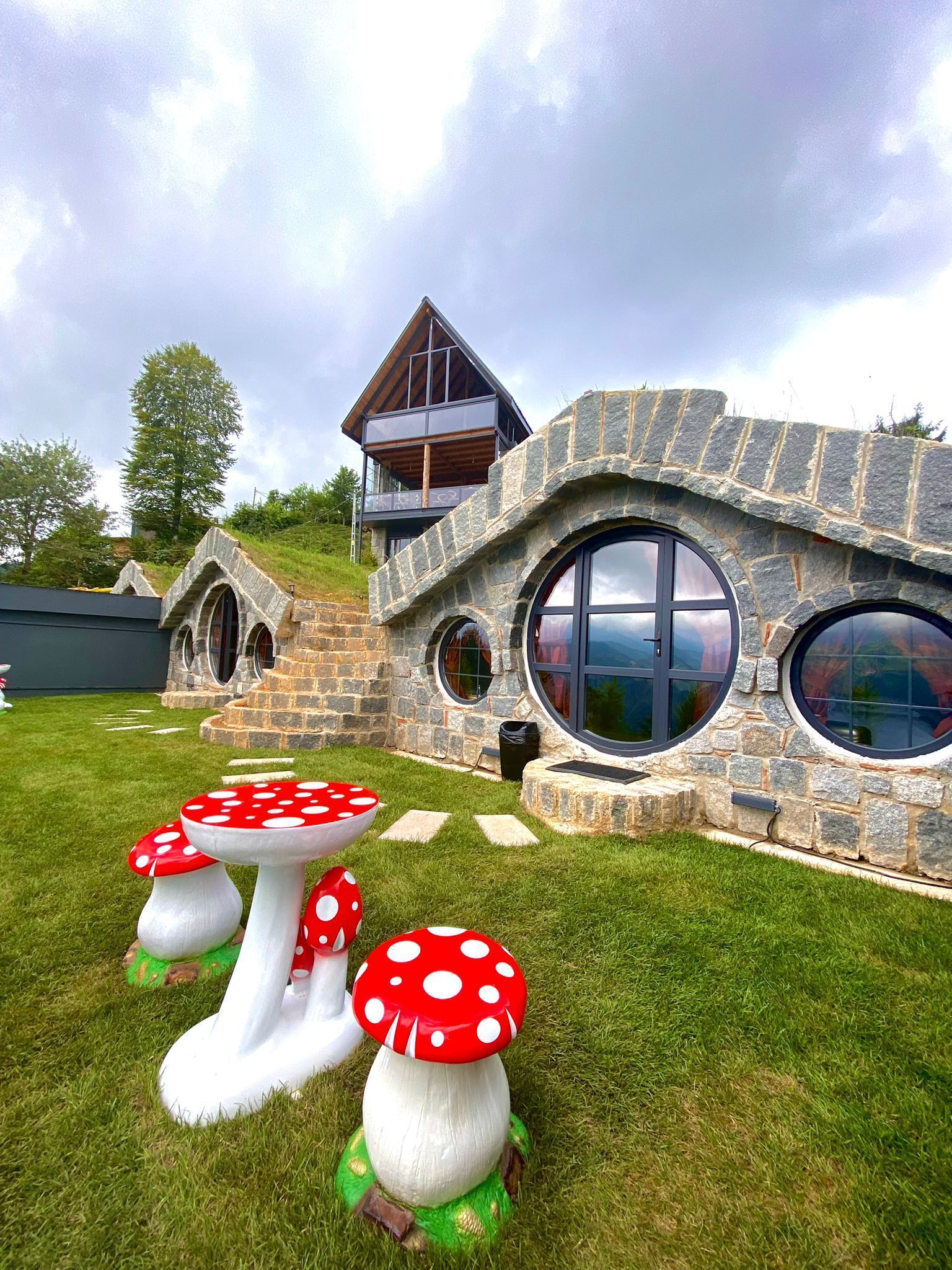 A house with a stone facade, large circular windows, and a wooden balcony.