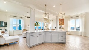 Una cocina amplia con una isla grande, armarios blancos e iluminación colgante.