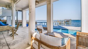 Un espacio al aire libre cubierto con piscina, mobiliario y vistas al mar.