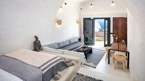 Una habitación moderna con sofá, cama, mesa de madera y vista al mar.