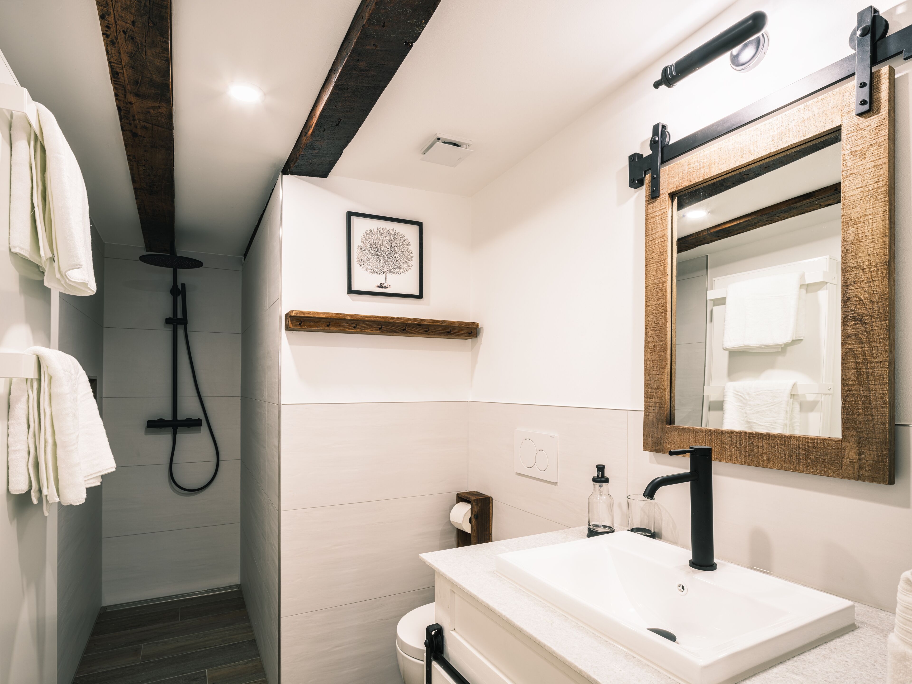 Un baño moderno con ducha, inodoro, lavabo y un espejo grande.