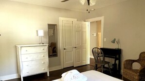 Een slaapkamer met een bed, een kaptafel, een stoel, een bureau en twee deuren.