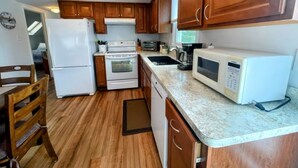 Una cocina compacta con armarios de madera, refrigerador, estufa, microondas y un lavamanos.