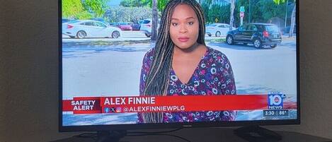 A television screen displaying a news broadcast with a reporter named Alex Finnie.