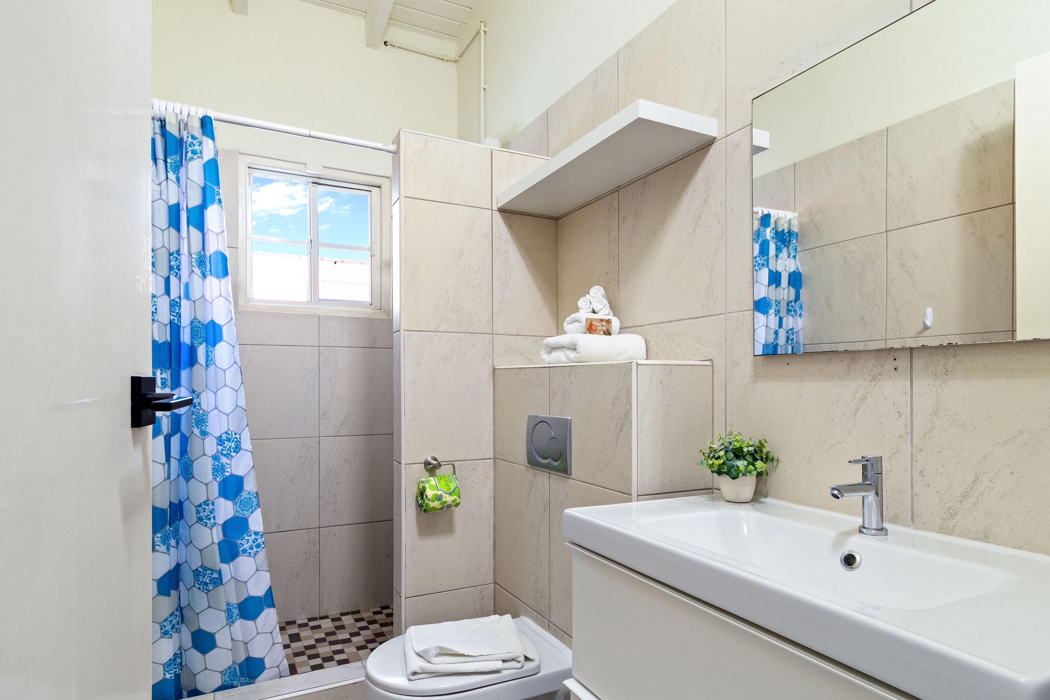 Een moderne badkamer met douche, toilet, wastafel en spiegel.