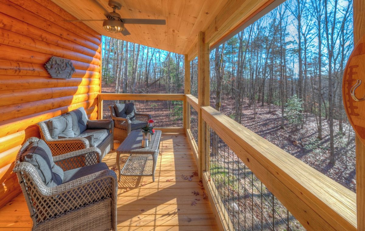 Una baita di legno con veranda, mobili in vimini e vista sulla foresta.