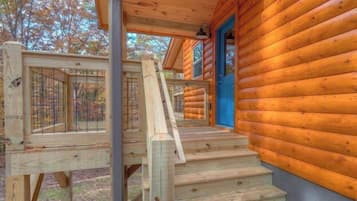 A wooden cabin with a wooden staircase leading to a blue door.