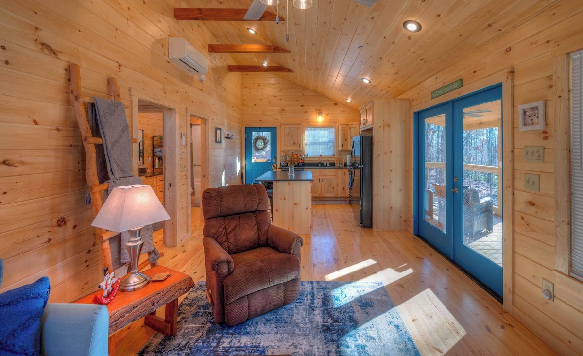 Interior de una cabaña de madera con una sala de estar acogedora, una cocina y un comedor.