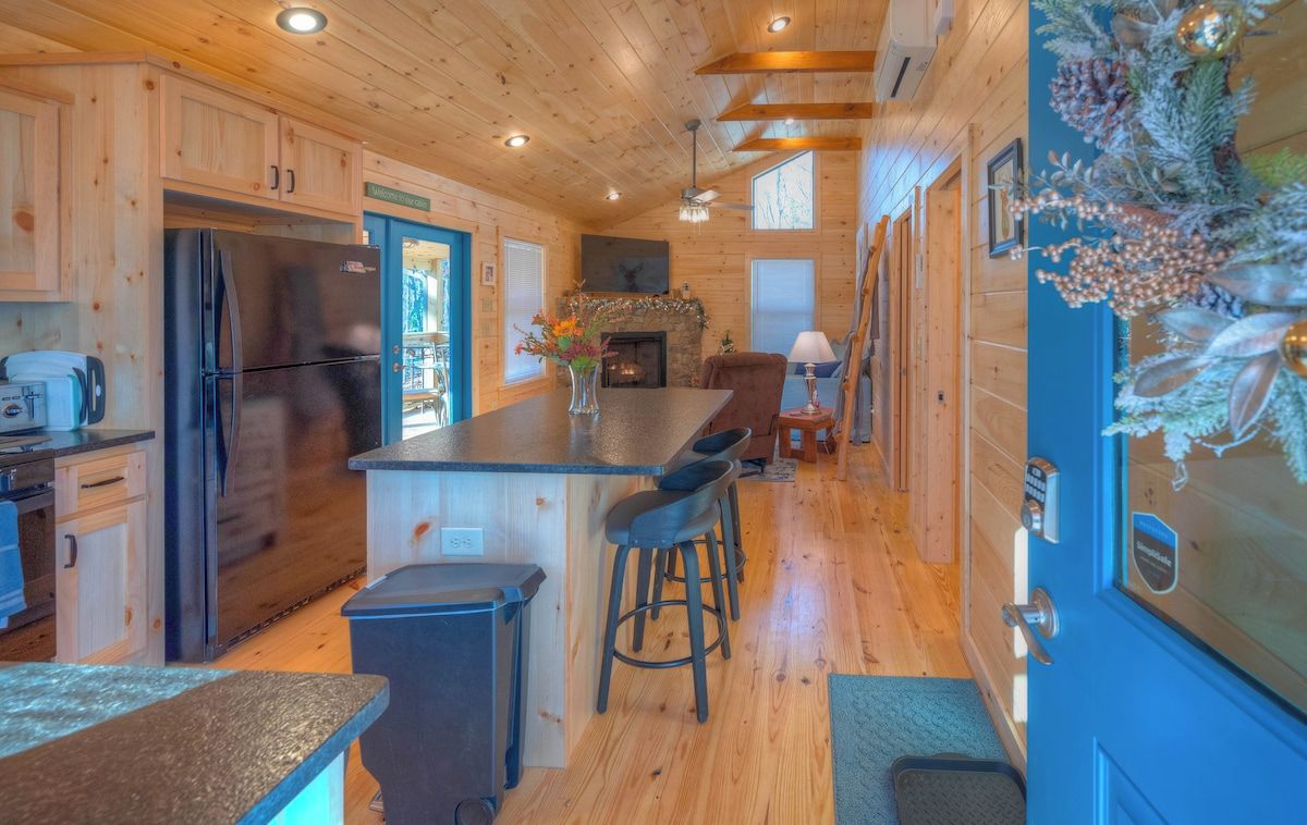 A wooden cabin interior with a kitchen, bar area, and a fireplace.