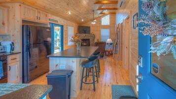 A wooden cabin interior with a kitchen, bar area, and a fireplace.