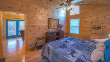 A wooden cabin room with a bed, dresser, and a ceiling fan.