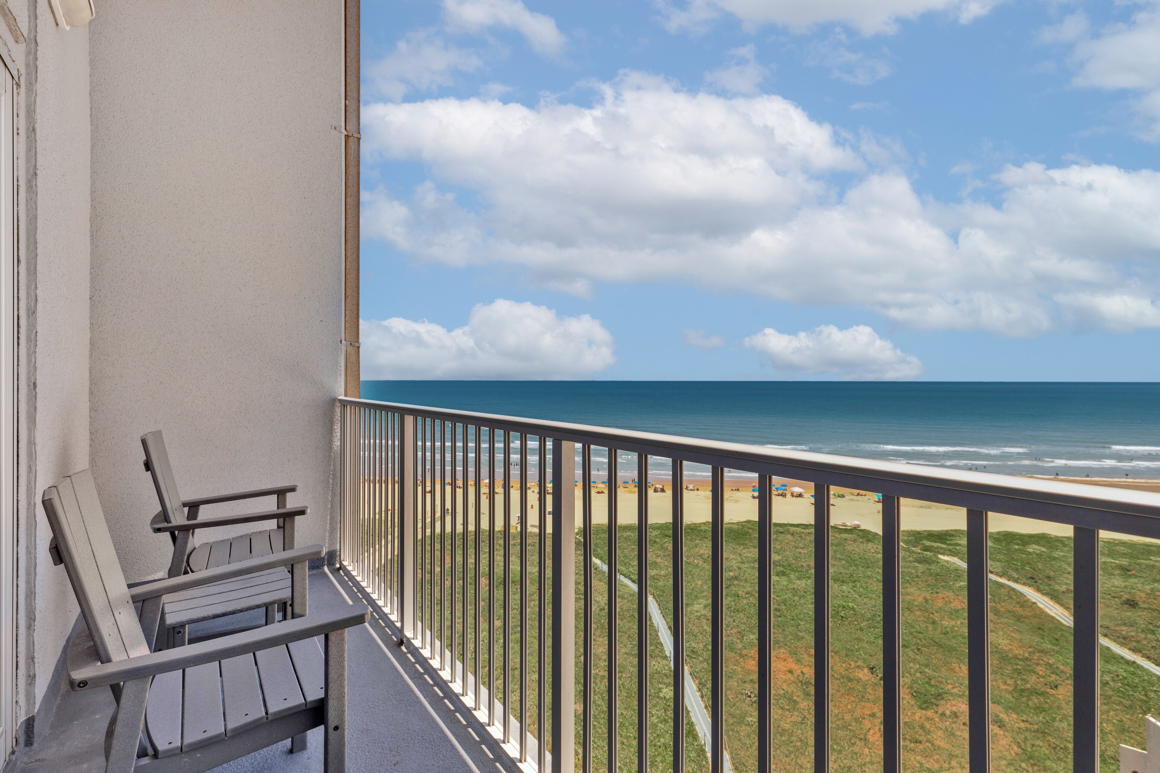 A balcony with a view of the beach and ocean.