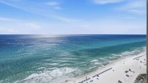 A beach with clear blue water, a sandy shore, and a row of beach chairs.