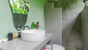 A bathroom with a white sink, a large mirror, a toilet, and a shower area.