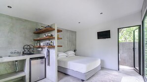 A modern room with a bed, a small kitchenette, and a large window.