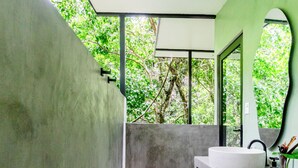 A bathroom with a concrete wall, a round sink, and a toilet.