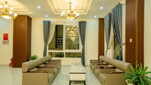Un vestíbulo moderno de hotel con sofás color beige, una mesa de centro y un candelabro.