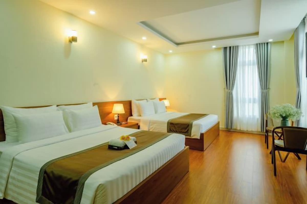 Quarto de hotel com duas camas, uma escrivaninha e uma cadeira.