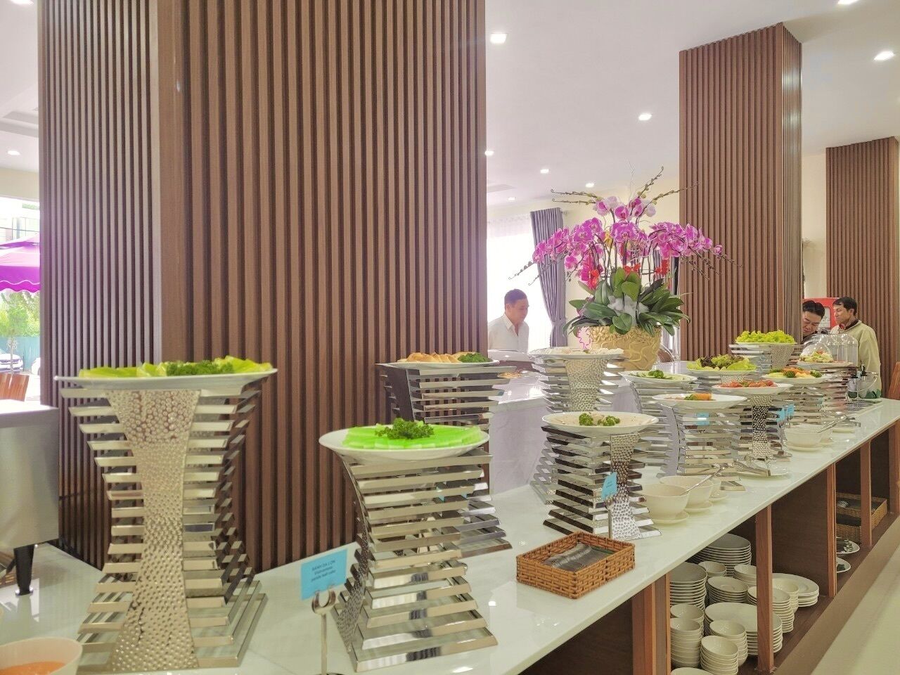 Ein reichhaltiges Buffet mit verschiedenen Speisen und einer Orchideen-Dekoration in der Mitte.