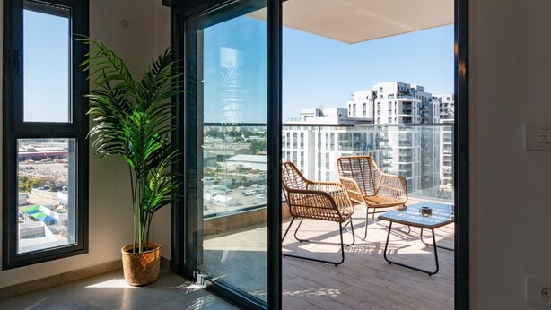 Egy balkon, rajta egy virágtartóban lévő növény, két fonott szék és egy kis asztal.