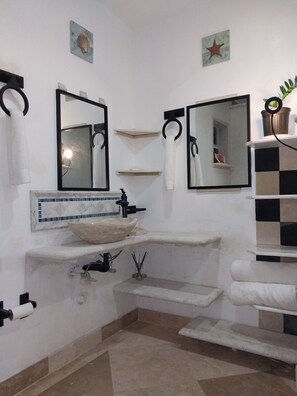 A bathroom with a white sink, two mirrors, a towel rack, and a small shelf with a decorative item. - Grace Bay beach area Apartment (Leeward Palms)