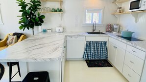 A compact kitchen with white cabinetry, a marble countertop, a sink, a microwave, and a small window. - Barn Loft on Gated Horse Farm (Greenville)