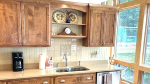Una cocina con armarios de madera, un lavamanos de acero inoxidable, una cafetera y un lavavajillas.