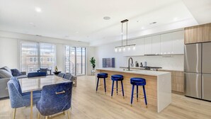 A modern kitchen with a central island, bar stools, and stainless steel appliances. - Capitol View 3 Penthouse with Rooftop (Washington)