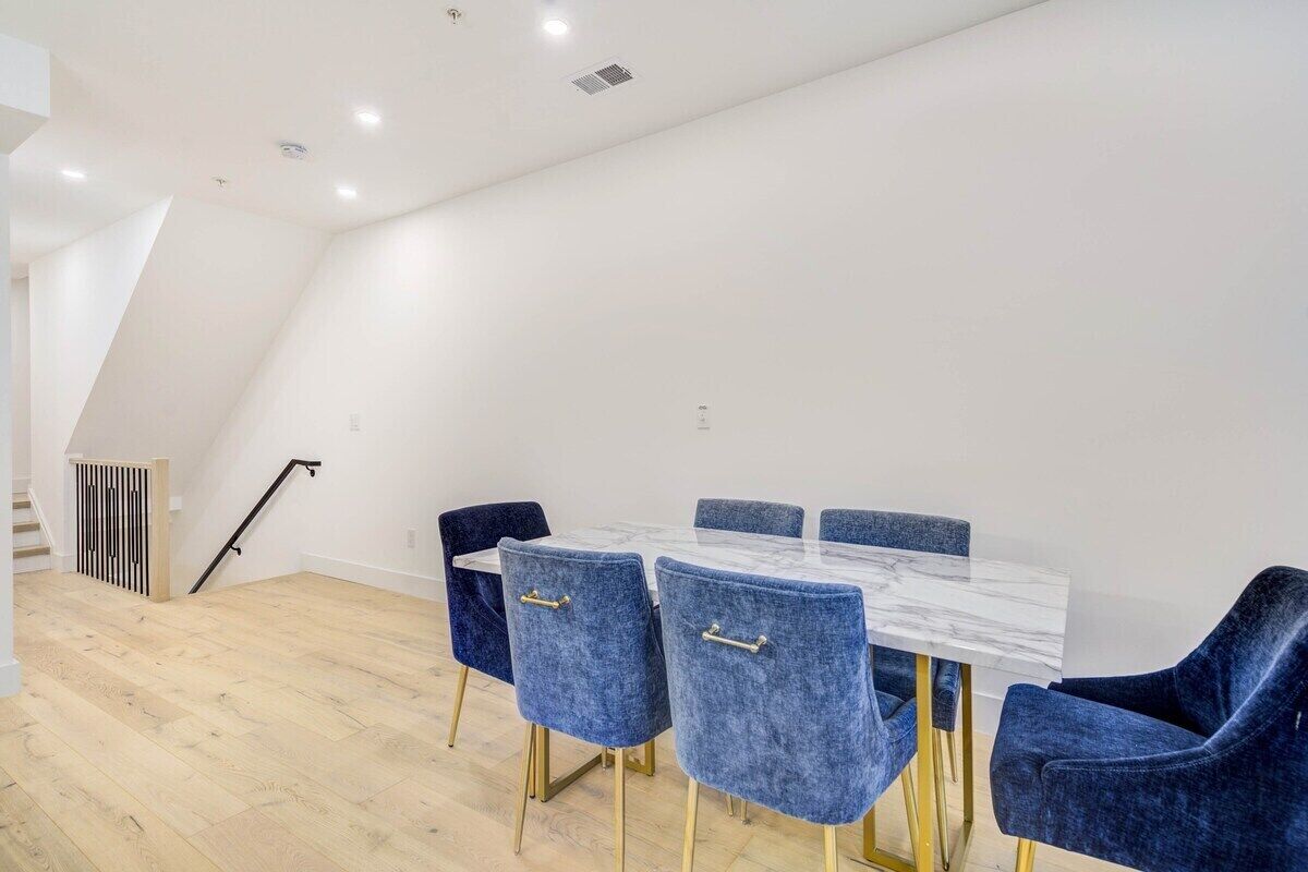 Un comedor con una mesa de mármol blanco y sillas de terciopelo azul.