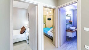Ein Hotelzimmer mit Bett, Nachttisch und einem Badezimmer mit Waschbecken und Spiegel.