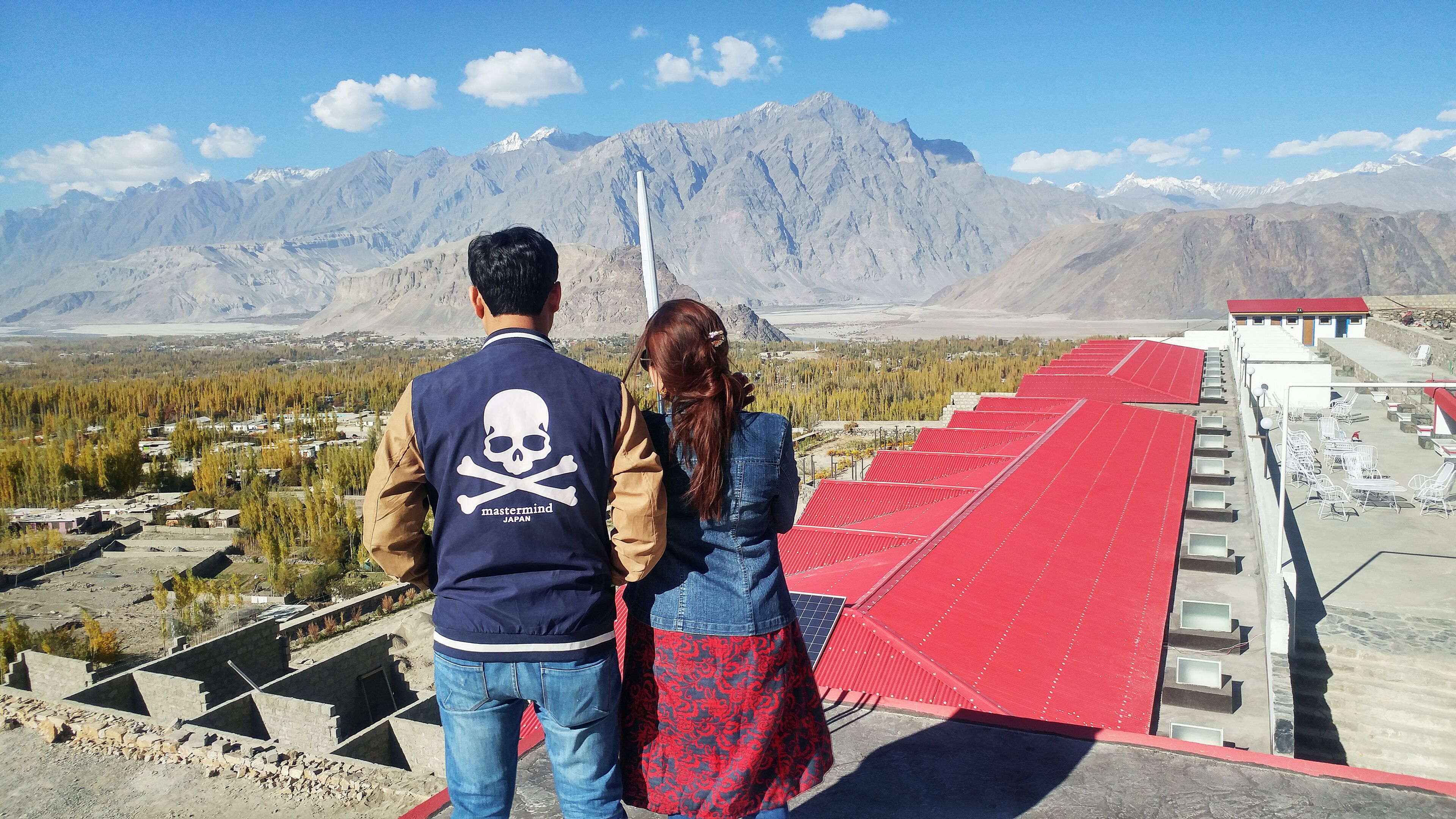 Un couple admire un paysage montagneux depuis un point de vue élevé.