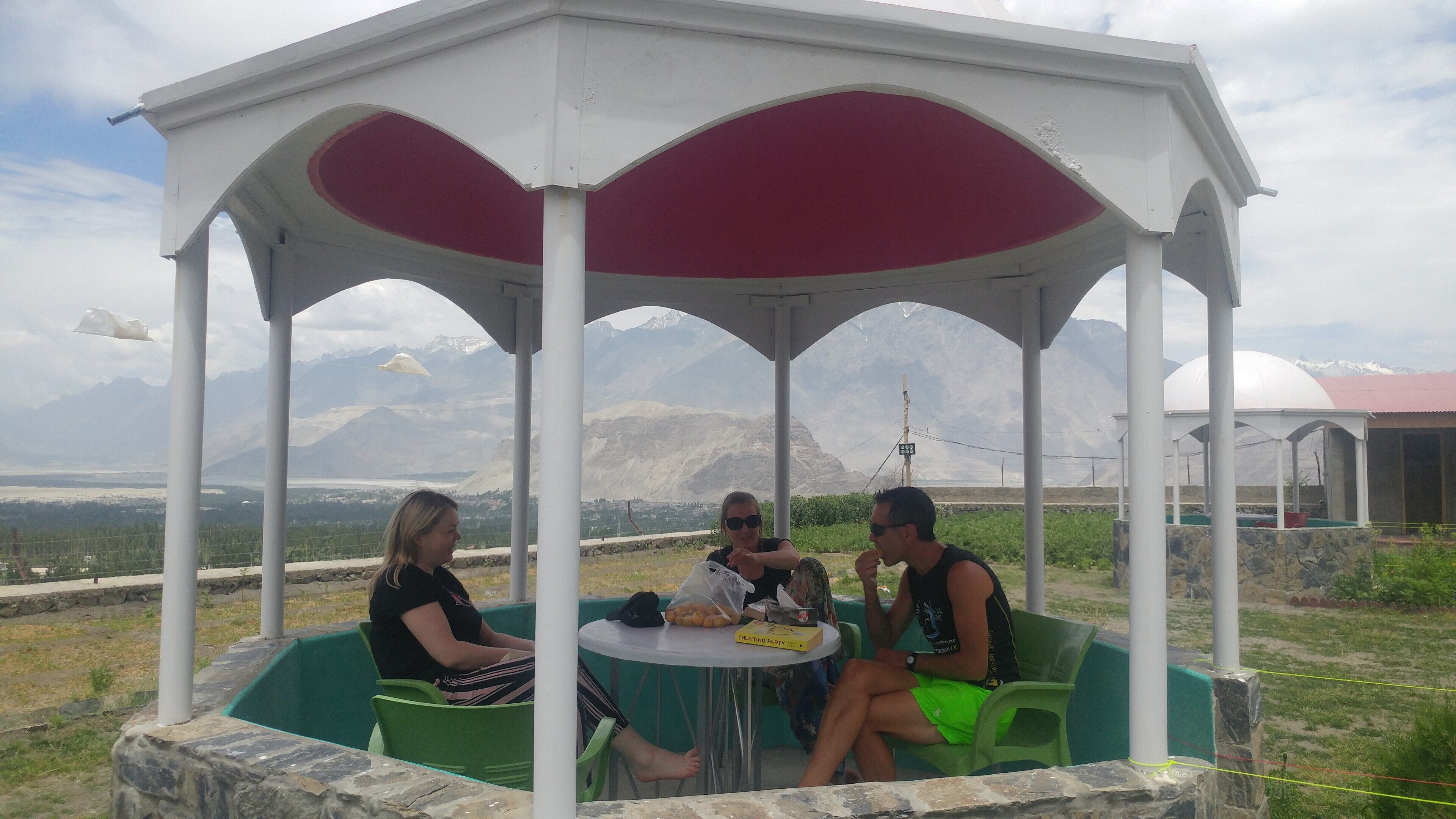 A gazebo with a table and chairs, surrounded by a mountainous landscape.